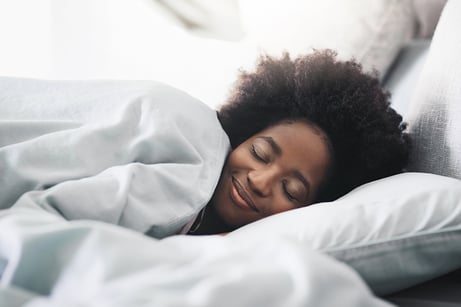 woman sleeping in bed w/ smile on her face